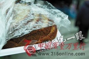 ■解開保鮮膜,蛋糕一角有顆耗子屎(紅圈處)。重慶晚報記者 陸綱 攝